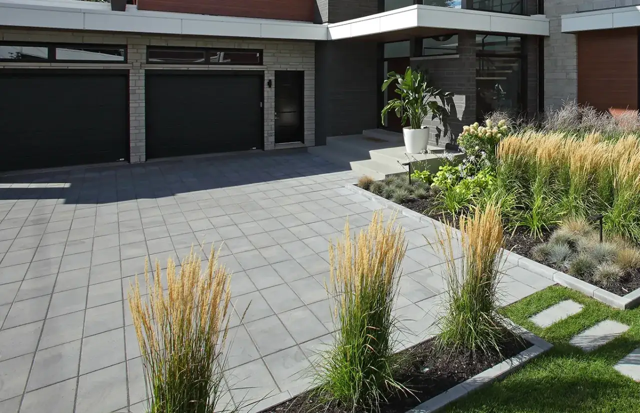 Id&eacute;e am&eacute;nagement jardin devant maison : all&eacute;e pav&eacute;e moderne, garage double, et jardin de gramin&eacute;es luxuriant.