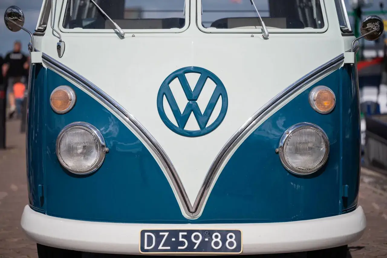 Klasyczny VW T2 w kolorze białym i niebieskim, z charakterystycznym logo. Gotowy na przygodę!