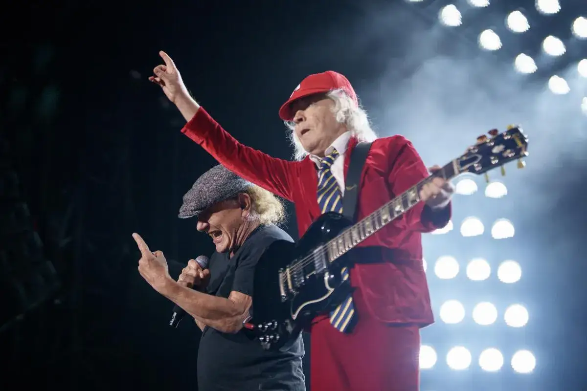 Angus Young und Brian Johnson von AC/DC rocken die B&uuml;hne mit bekannten Liedern. Angus spielt Gitarre, Brian singt ins Mikrofon.