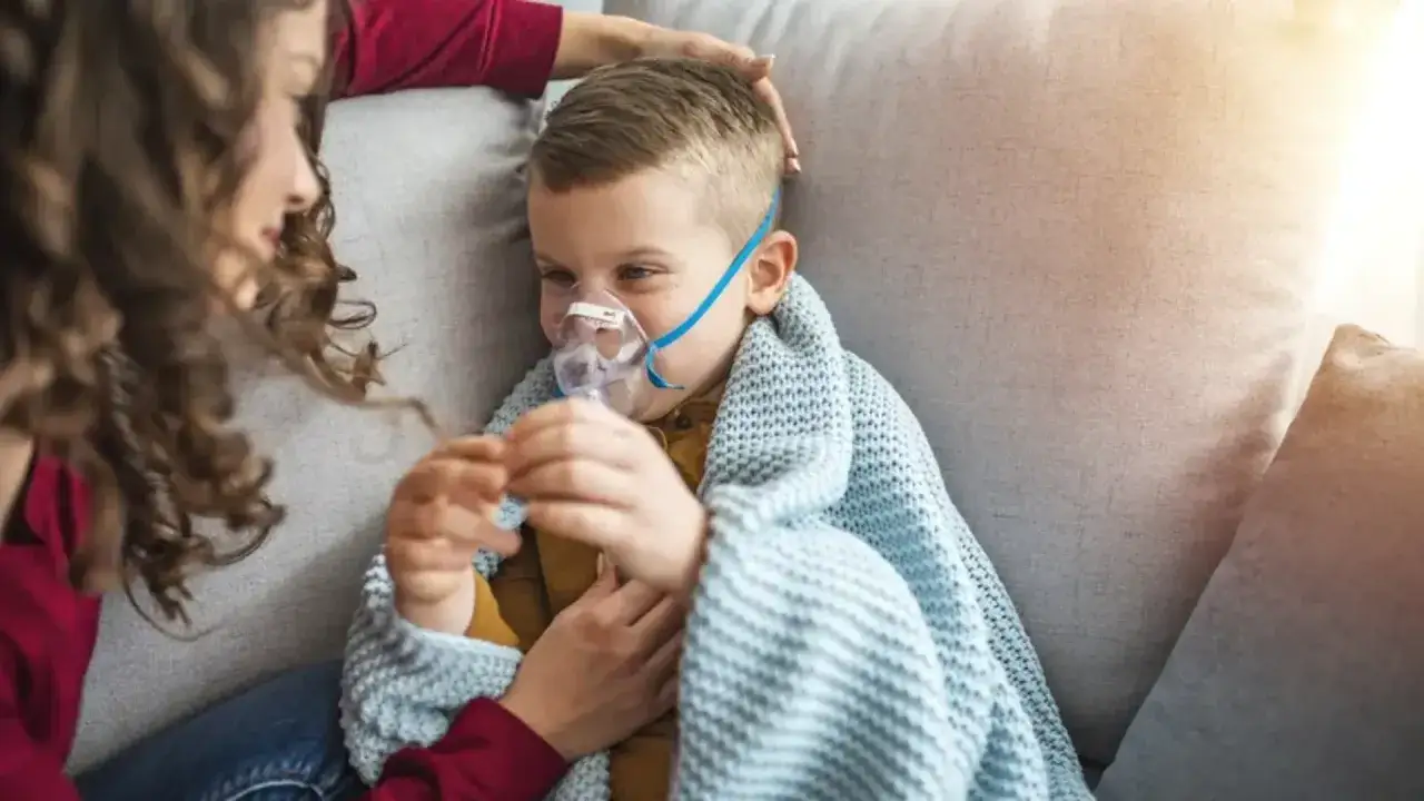 Chłopiec z maską inhalatora, otulony kocem, czuje się jakby dopadła go klątwa Ondyny. Mama czule go głaszcze.