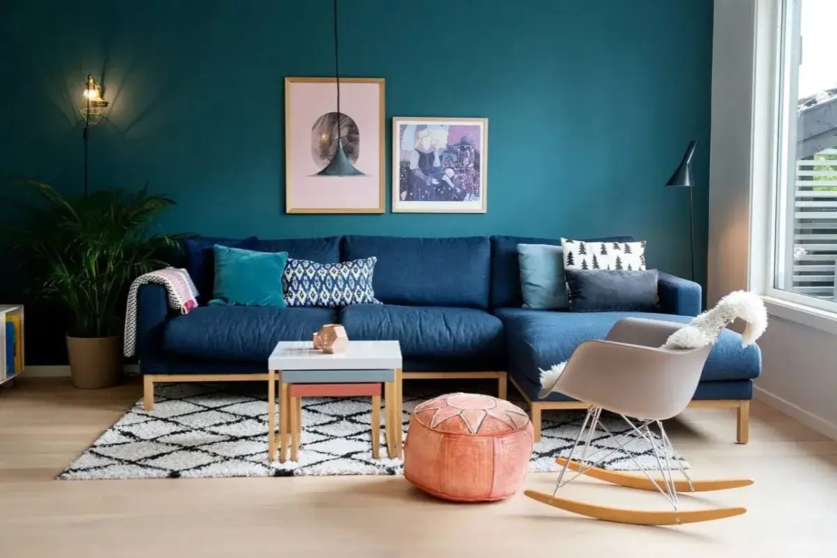 Un accogliente salotto con divano blu, tappeto geometrico e pareti color ral ottanio.