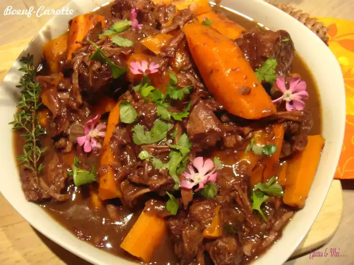 Un plat réconfortant de boeuf carottes mijoté, garni de persil frais et de petites fleurs roses.