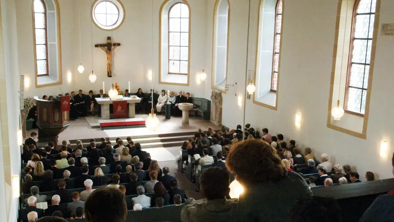 Menschen versammeln sich in einer Kirche, um die Botschaft des Evangeliums zu h&ouml;ren. Ein Kreuz h&auml;ngt &uuml;ber dem Altar.