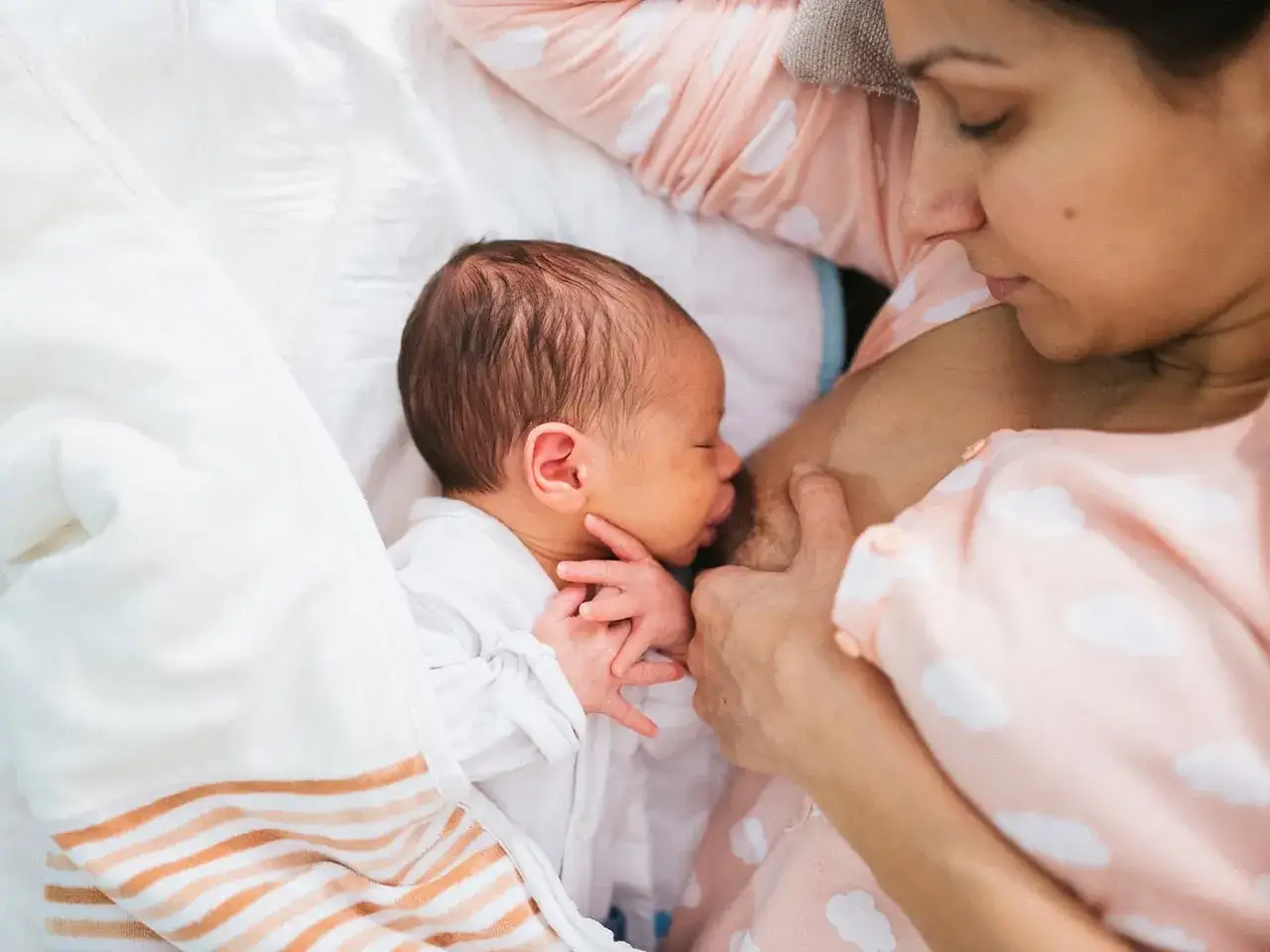 Mama tuli tuli karmienie na leżąco. Maluszek śpi wtulony w jej pierś, otulony miękkim kocykiem.