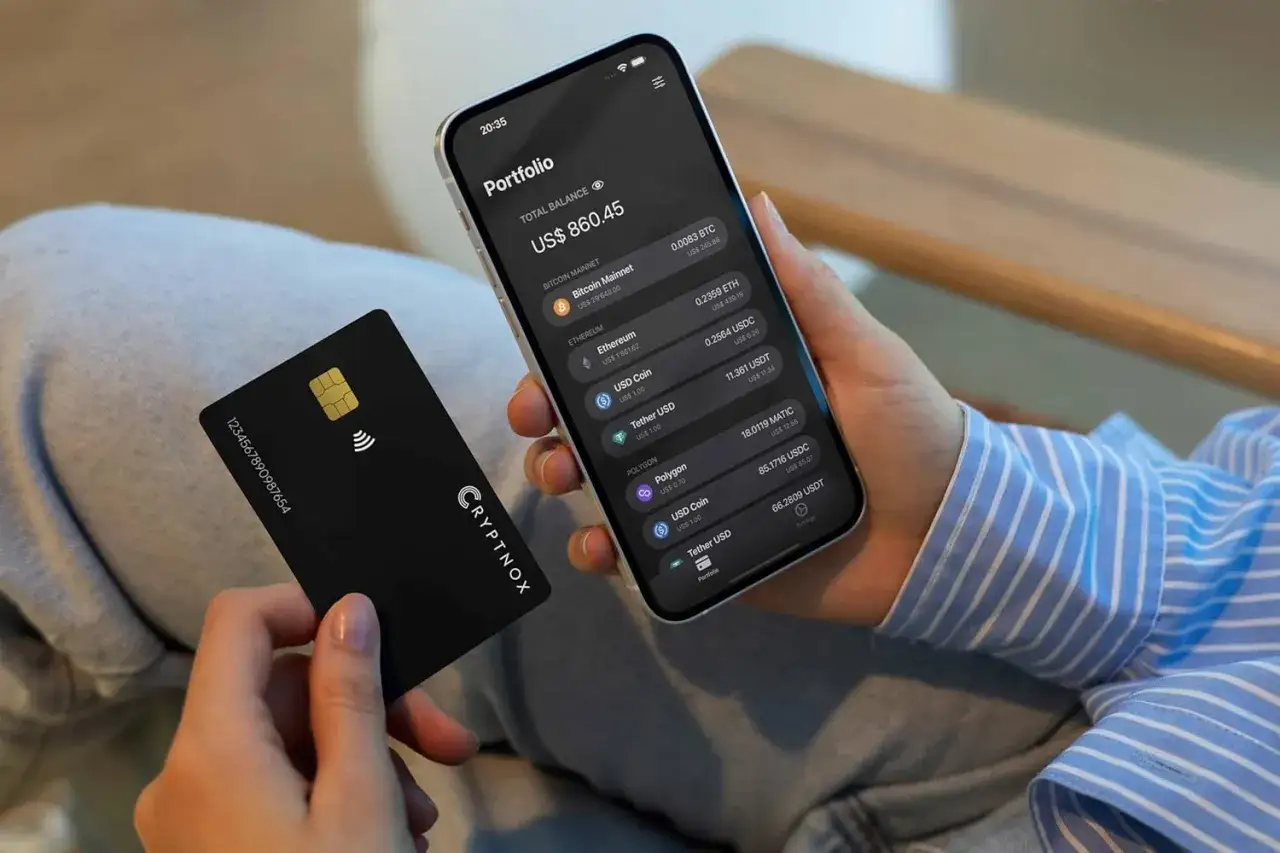 Persona revisa su portafolio de criptomonedas en el móvil, con una tarjeta negra de CRYPTNOX. Una forma moderna de invertir en cripto.