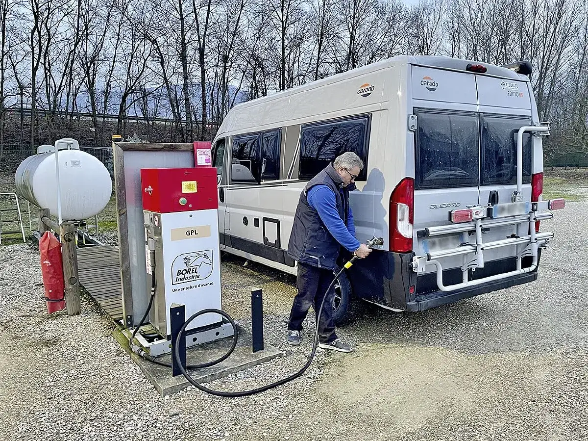 Un homme fait le plein de son camping-car à une borne GPL. Respect de la réglementation GPL camping-car pour un voyage serein.