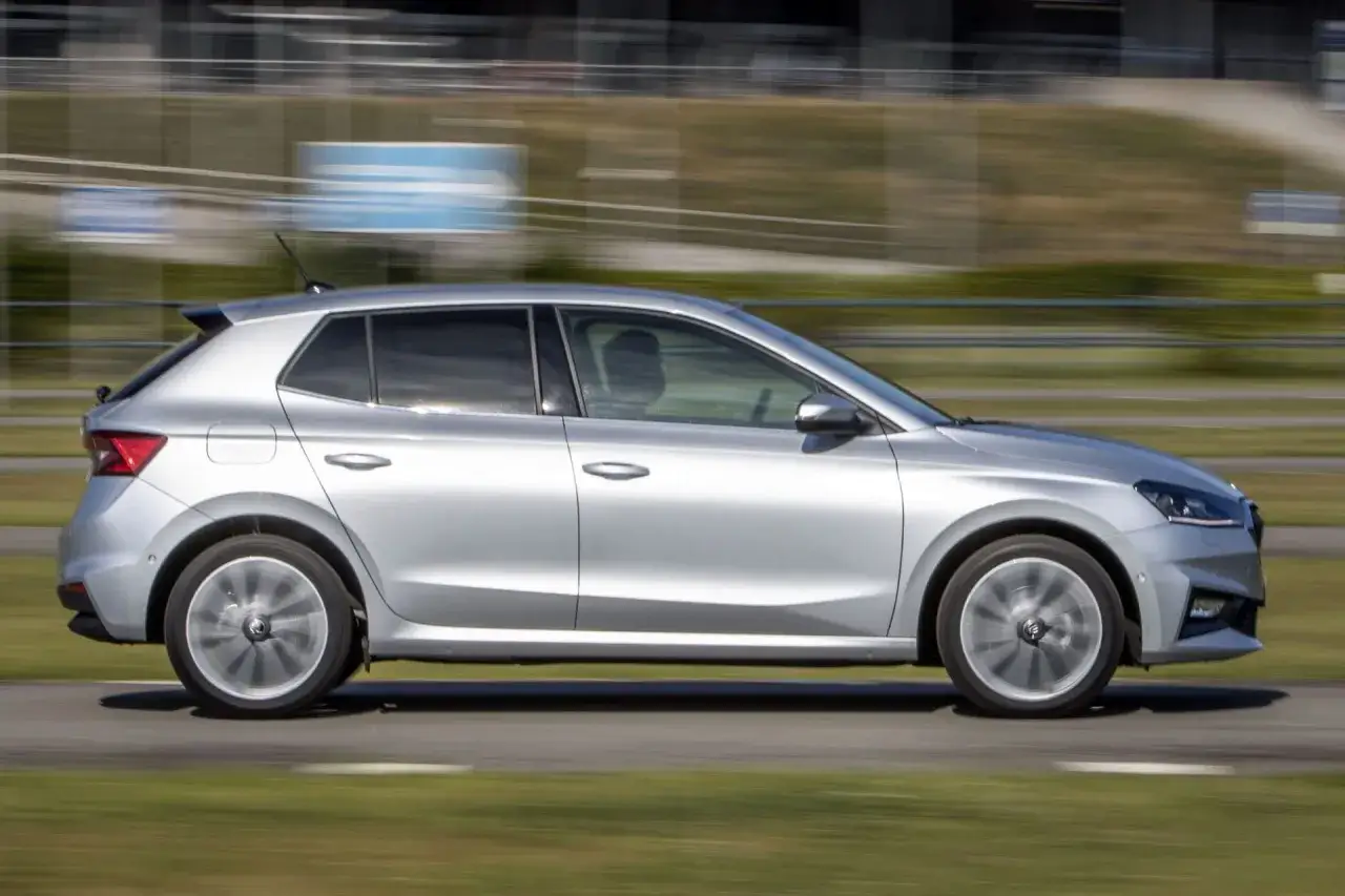 Srebrna Skoda Fabia 4 w ruchu, z rozmytym tłem toru wyścigowego.