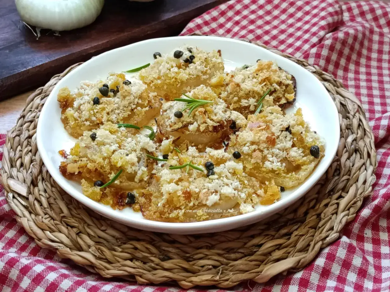 Deliziose cipolle al forno, dorate e croccanti, guarnite con rosmarino e pepe nero. Un contorno saporito e invitante.