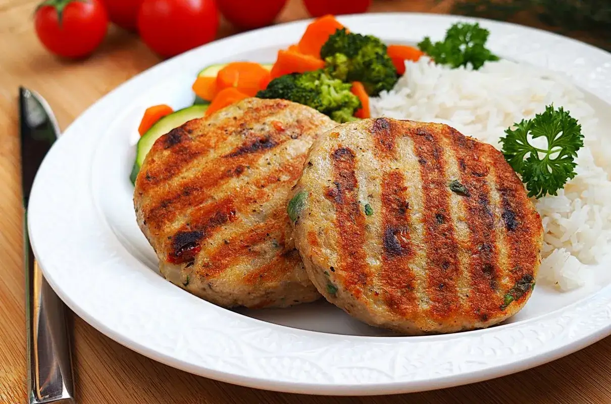 Dwa soczyste kofta kebab z grilla, podane z ryżem i warzywami.