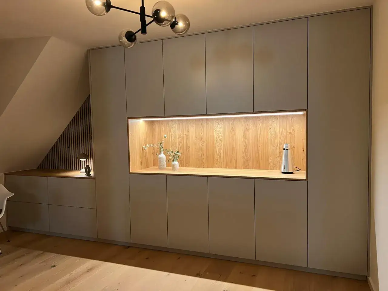 Moderne Einbauschränke gestalten eine gemütliche Schlafnische mit beleuchtetem Holzakzent und Deko.