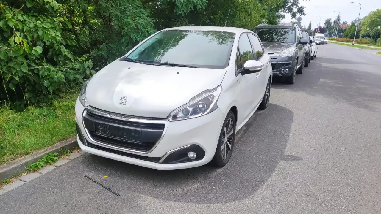 Biały Peugeot 208 zaparkowany przy drodze. Obok inne samochody. Czy to Twój nowy nabytek?