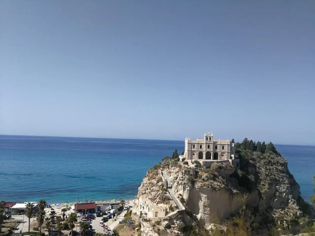 Vue panoramique de Tropea, Italie, avec une église perchée sur une falaise surplombant la mer.
