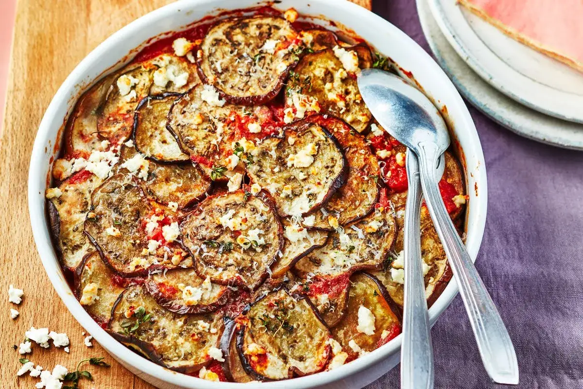Un plat de moussaka végétarienne appétissant, avec des couches d'aubergines grillées, de sauce tomate et de fromage émietté, prêt à être servi.