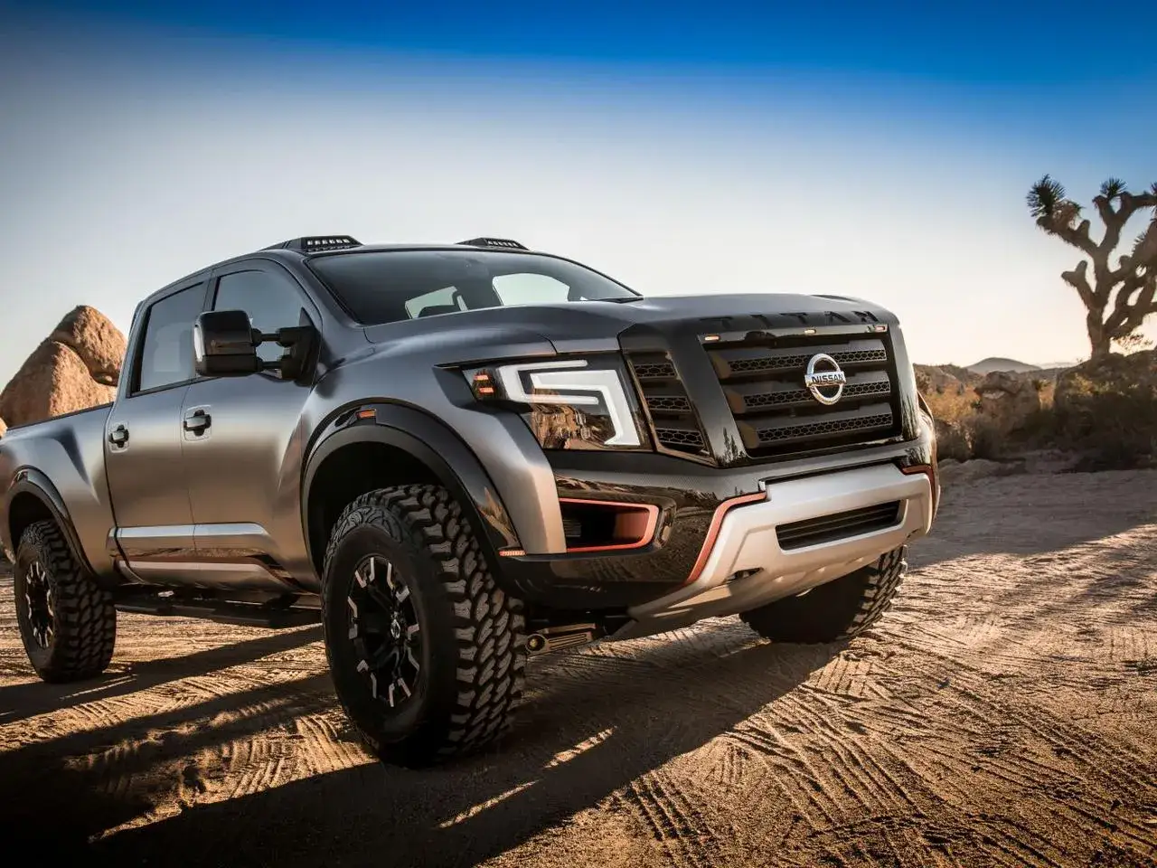 Potężny Nissan Titan w szarym kolorze, gotowy na terenowe wyzwania, z charakterystycznym grillem i oświetleniem.