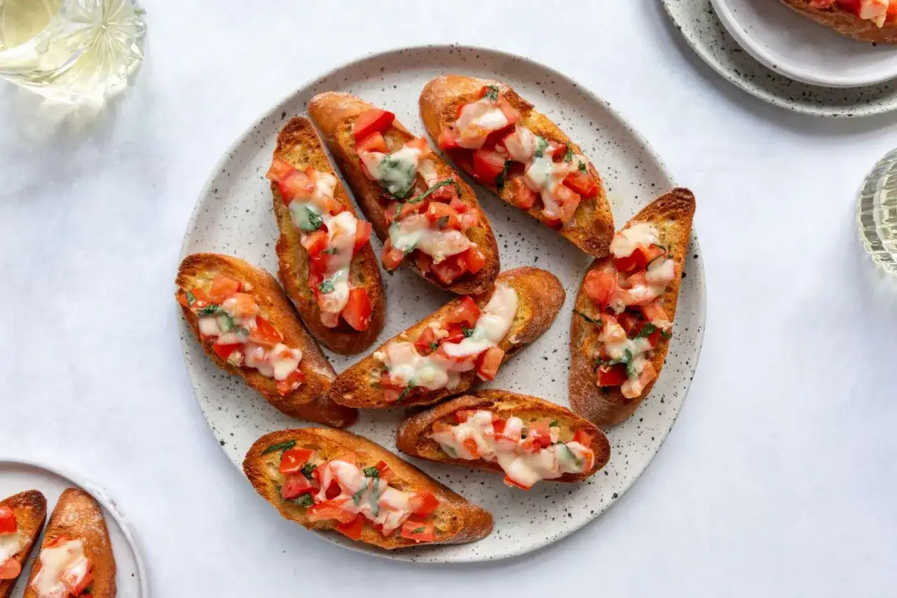 Ein Teller mit knusprigem Brot, belegt mit Tomaten, Basilikum und geschmolzenem Käse – ein klassisches Rezept für Bruschetta original italienisch.