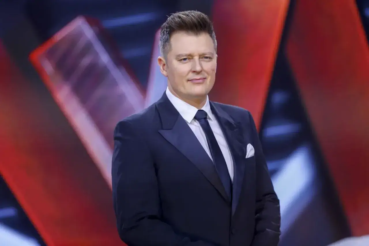 Rafał Brzozowski w eleganckim garniturze, gotowy do prowadzenia programu