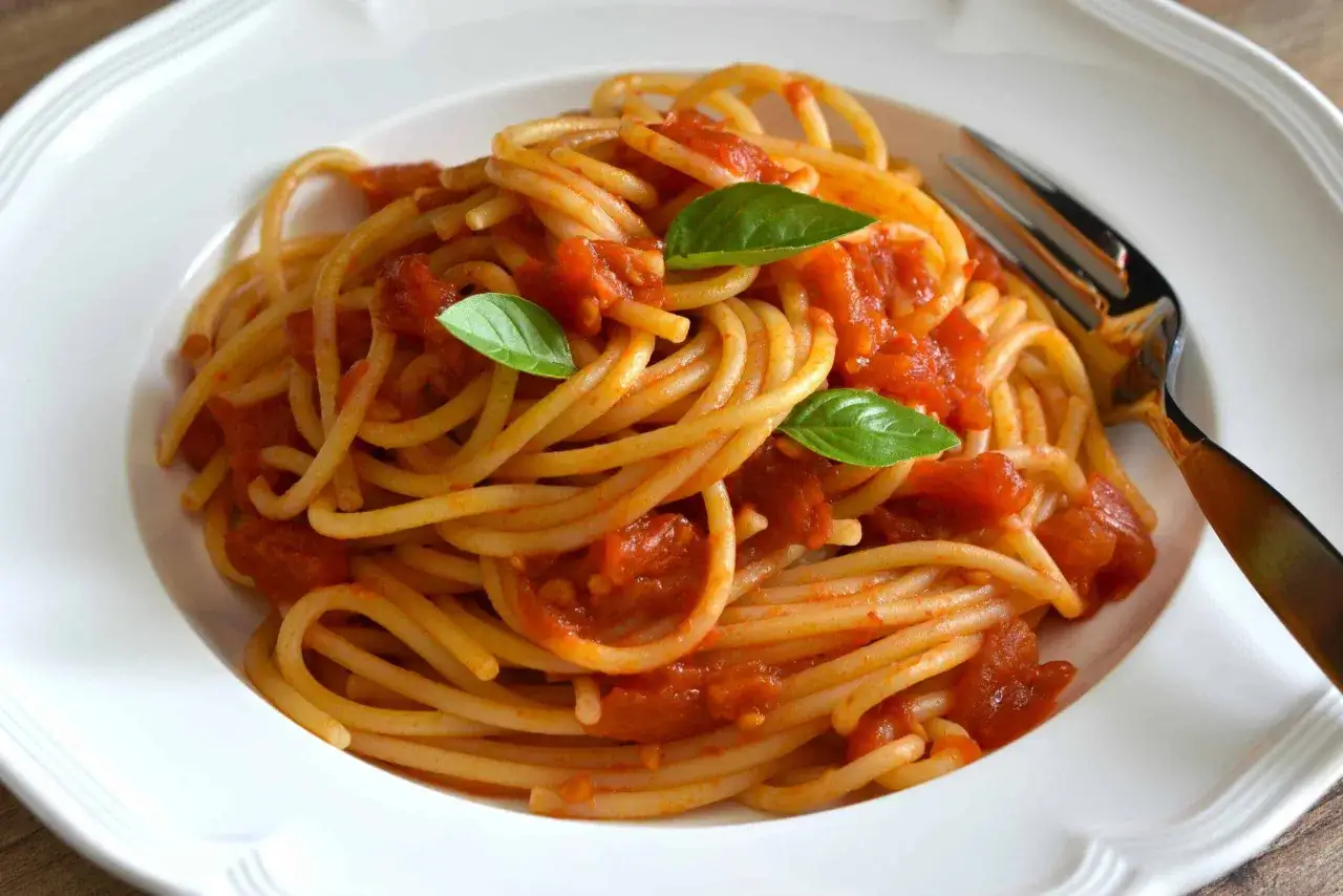 Ein Teller Spaghetti Napoli mit Tomatensauce und frischem Basilikum, bereit zum Genie&szlig;en.