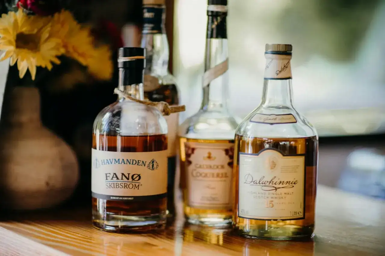 Butelki whisky na drewnianym stole. Jak degustować whisky żeby poczuć torf, wanilię i dym (metoda tulipana) - uchwycone w kadrze.