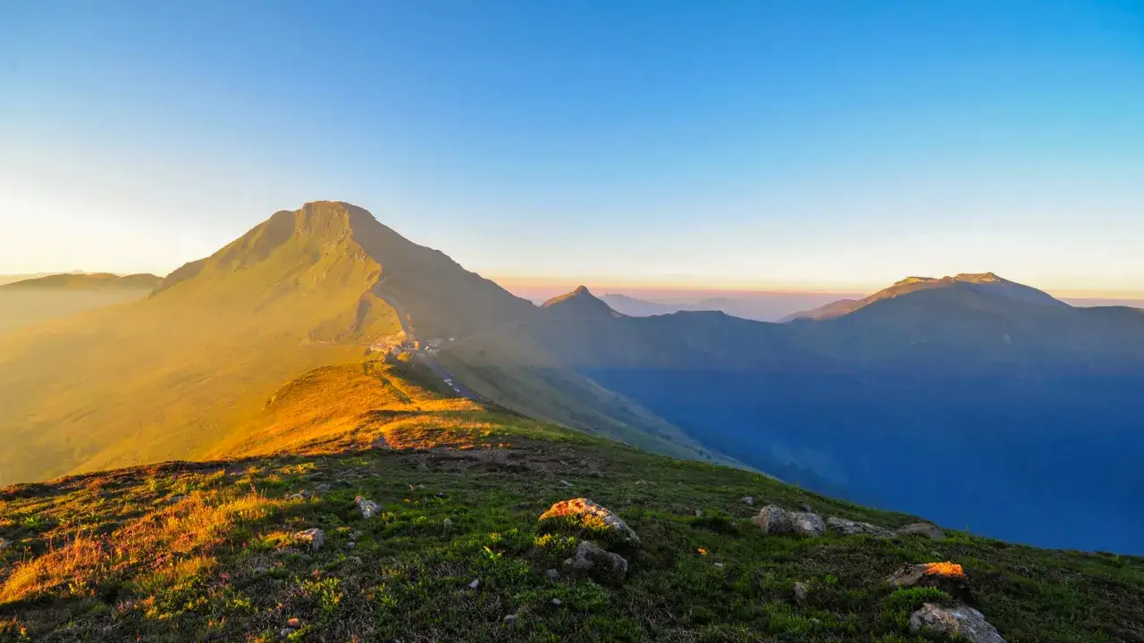 Lever du soleil sur le Puy Mary, id&eacute;al pour une randonn&eacute;e matinale. Les montagnes s'&eacute;tirent sous un ciel clair.