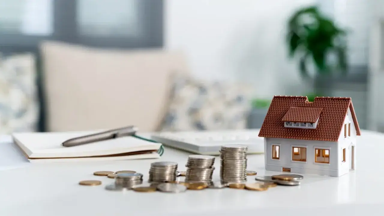 Modellino di casa, monete e taccuino. Si pensa al **plafond casa disabili tasso interesse** per un futuro acquisto.