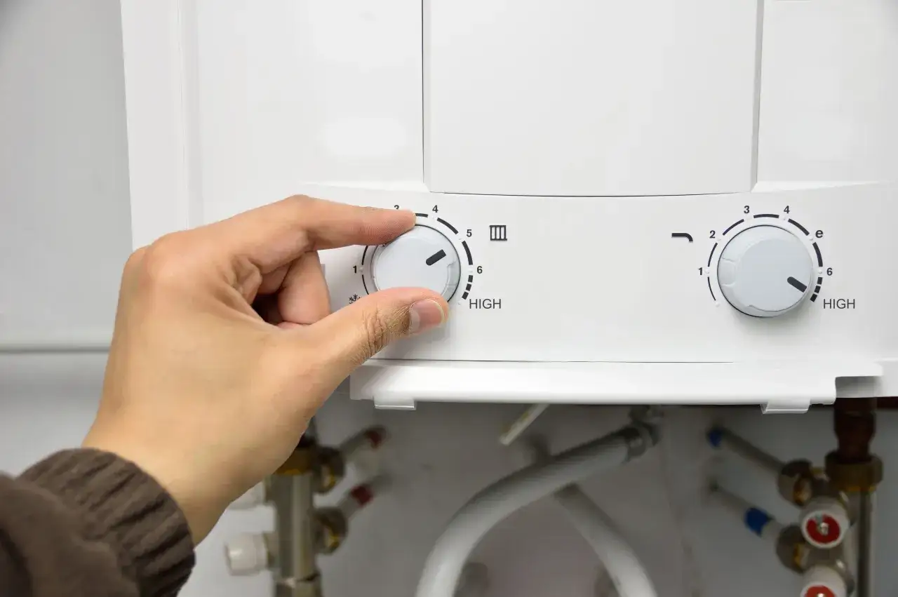 Mano ajustando el dial de temperatura de un termo el&eacute;ctrico. Se acerca el momento de desmontar el termo el&eacute;ctrico para su mantenimiento.