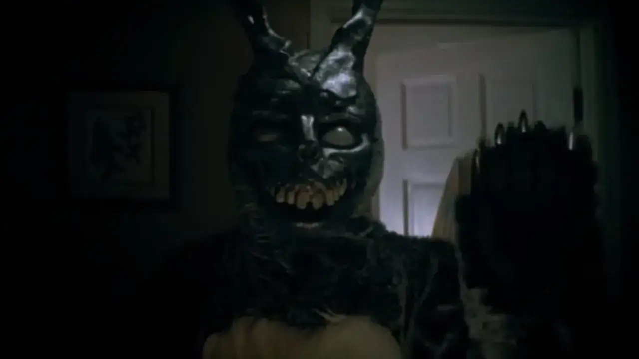 Frank, w przerażającym kostiumie królika z filmu Donnie Darko, pojawia się w mroku, ostrzegając przed nadchodzącą zagładą.
