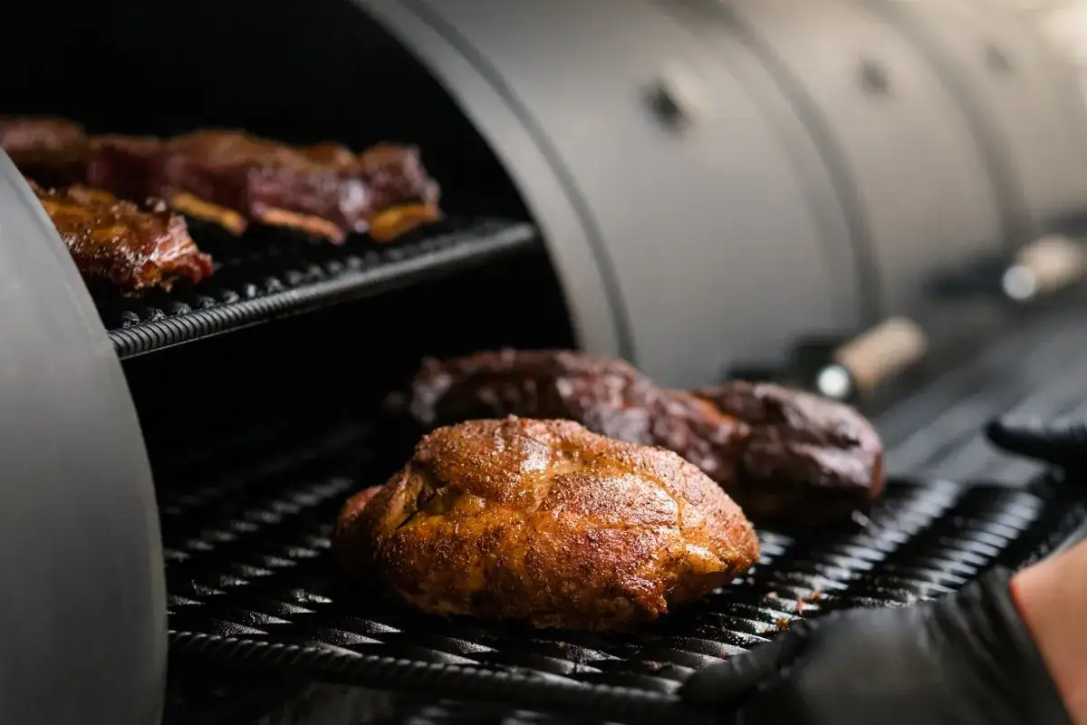 Un barbecue hivernal avec des c&ocirc;tes lev&eacute;es et un poulet r&ocirc;ti sur une grille.
