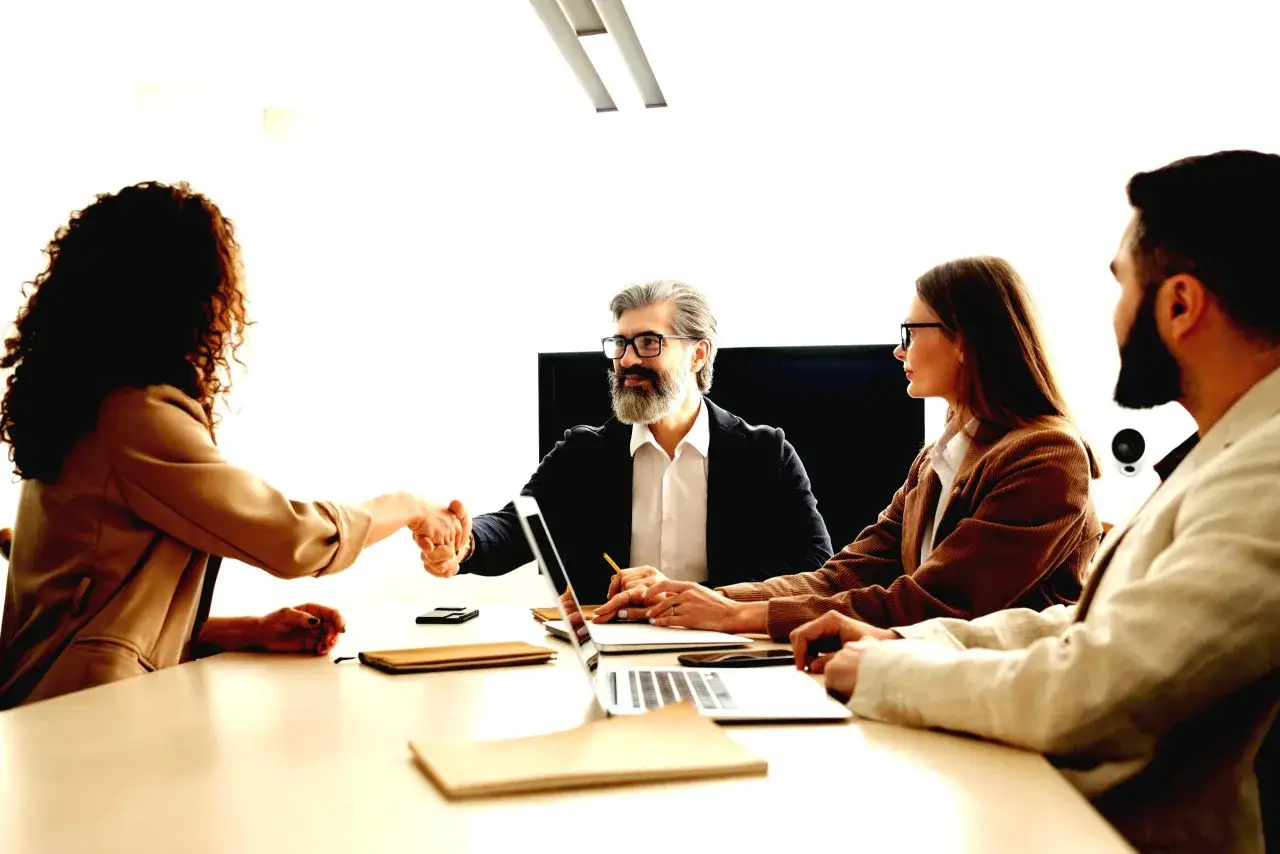 Biznesowe spotkanie, gdzie hr business partner ściska dłoń nowemu pracownikowi.