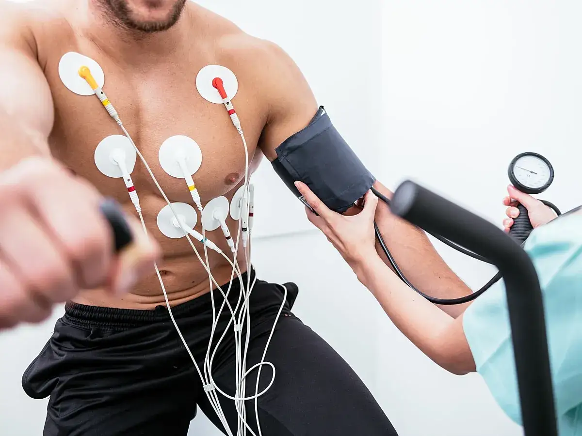 Badanie wysiłkowe: mężczyzna z elektrodami EKG i mankietem do pomiaru ciśnienia. Monitorowanie **wysokie ciśnienie po wysiłku**.
