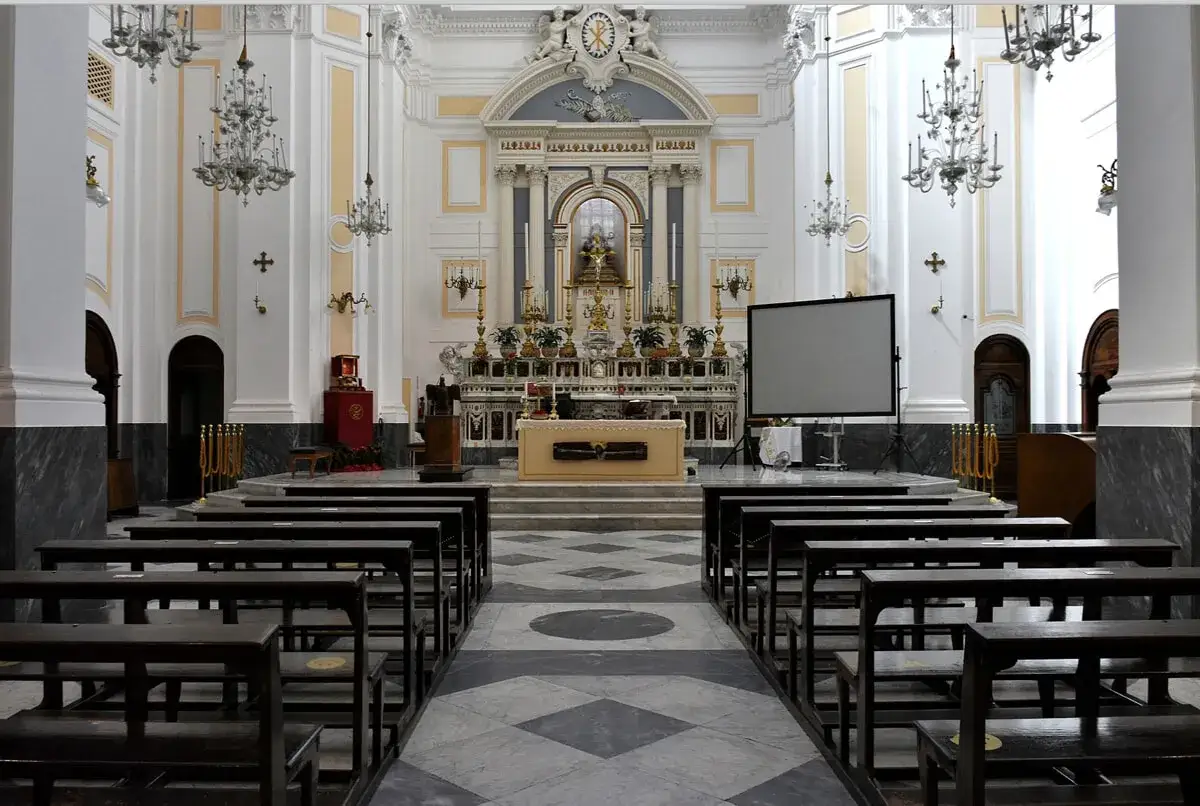 Interno di una chiesa, con panche in legno scuro e un altare imponente. Sembra una piccola Pompei al Vomero, con la sua solennità.