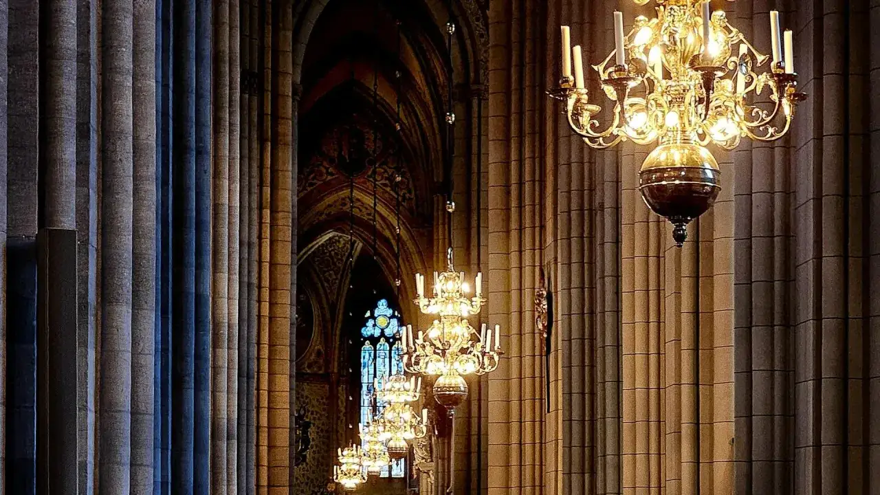 Gyllene ljuskronor hänger i rad längs pelarna i Uppsala domkyrka. Ett vackert program för en speciell kväll.