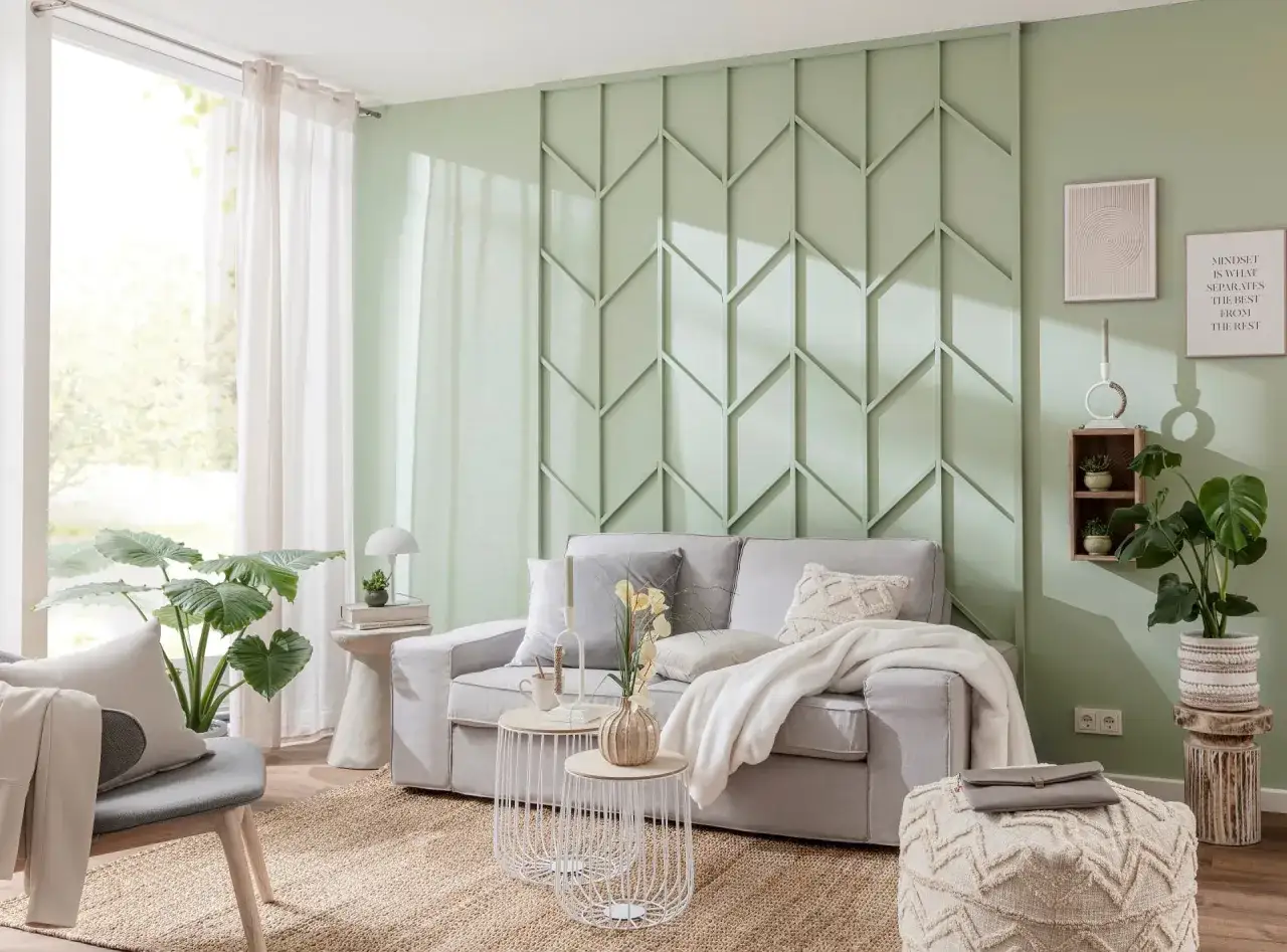 Eine stilvolle Wand hinter der Couch gestalten mit einem geometrischen Paneel in Mintgrün. Ein gemütliches Sofa mit Kissen und Decke lädt zum Entspannen ein.