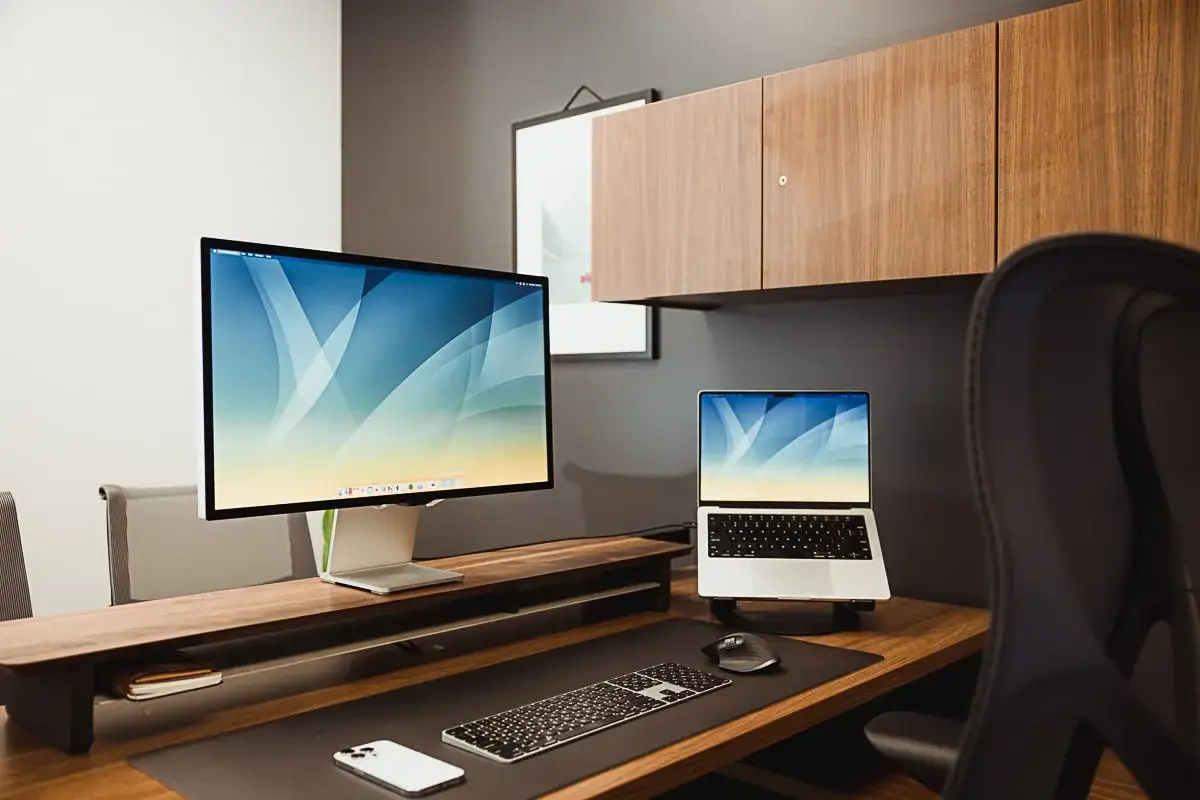 A clean, modern desk setup with a large monitor and laptop, perfect for focusing and learning how to avoid distractions.