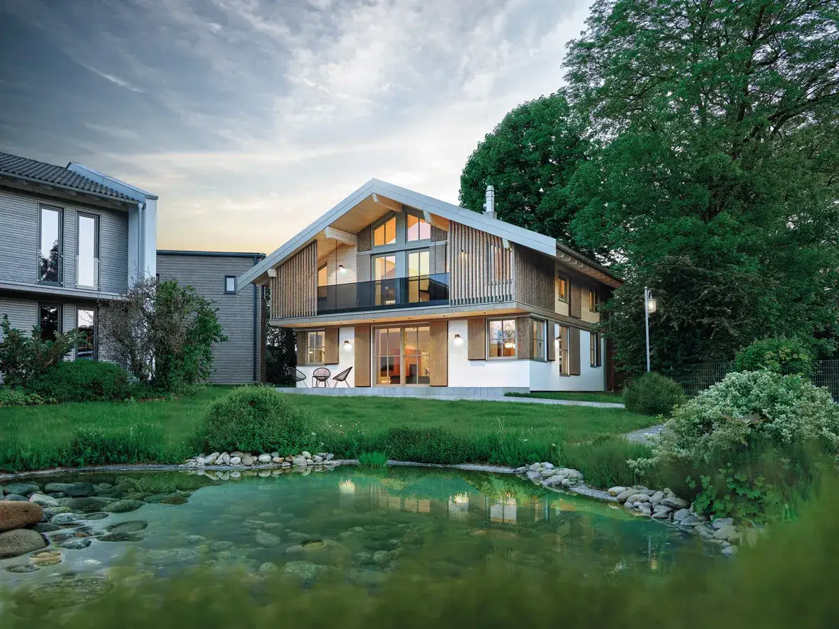Moderne haus stile mit Holzfassade und gro&szlig;em Teich. Ein Haus mit viel Glas und einem spitzen Dach.
