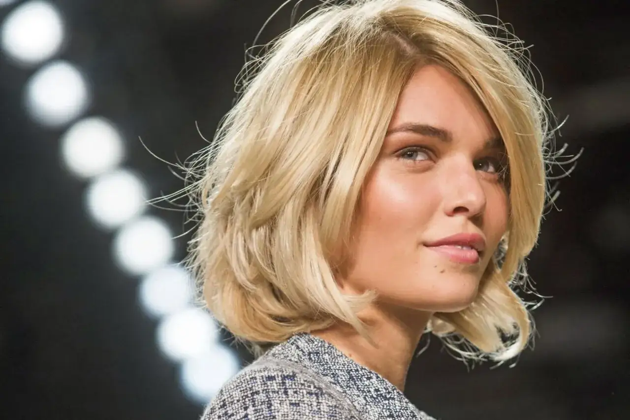 Blonde Frau mit einem lässigen, choppy bob Haarschnitt, blickt nach rechts.