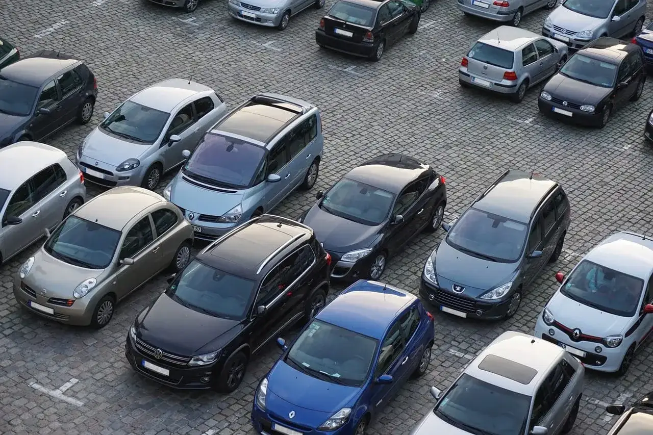 Widok z góry na parking, gdzie widać podział miejsca parkingowe we wspólnocie mieszkaniowej. Zaparkowane są różne samochody.