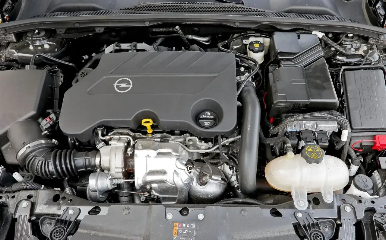 Silnik Opla Insignii, z charakterystycznym logo marki. To serce, które sprawia, że podróżowanie tym modelem jest przyjemnością, dowód na to, że Opel Insignia najlepszy silnik oferuje.
