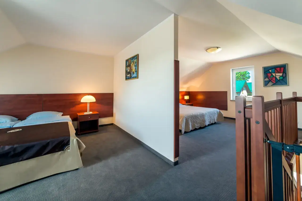 Przytulne apartamenty Fulay Karwia. Dwa pokoje z wygodnymi łóżkami, lampkami nocnymi i nowoczesnymi obrazami.