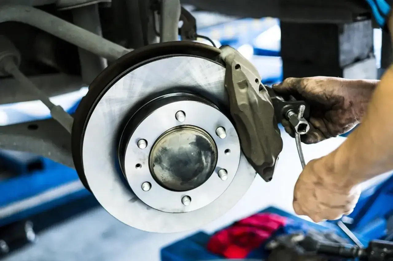 Mechanik dokonuje czyszczenia zacisków hamulcowych, używając klucza do precyzyjnej pracy.
