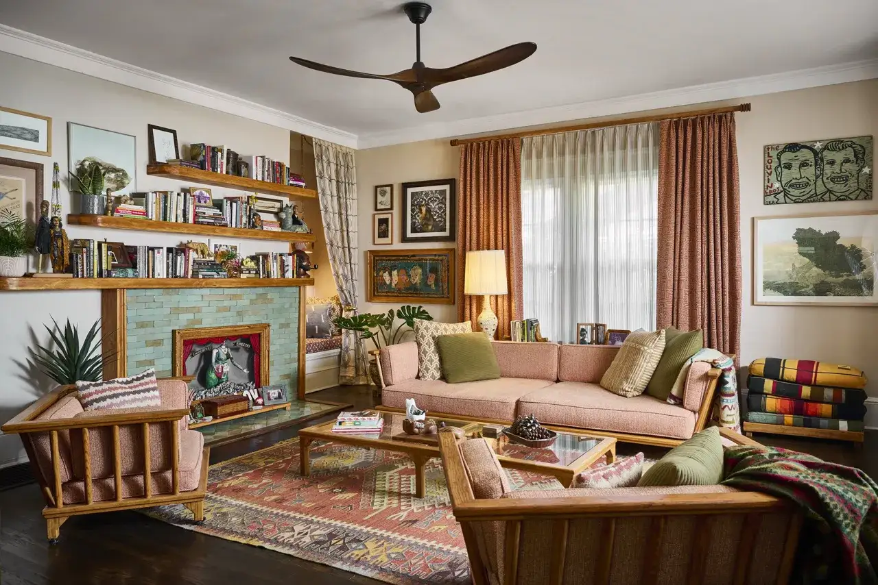 Cozy 1920s craftsman house living room with a pink sectional, wooden furniture, and a fireplace adorned with teal tiles.
