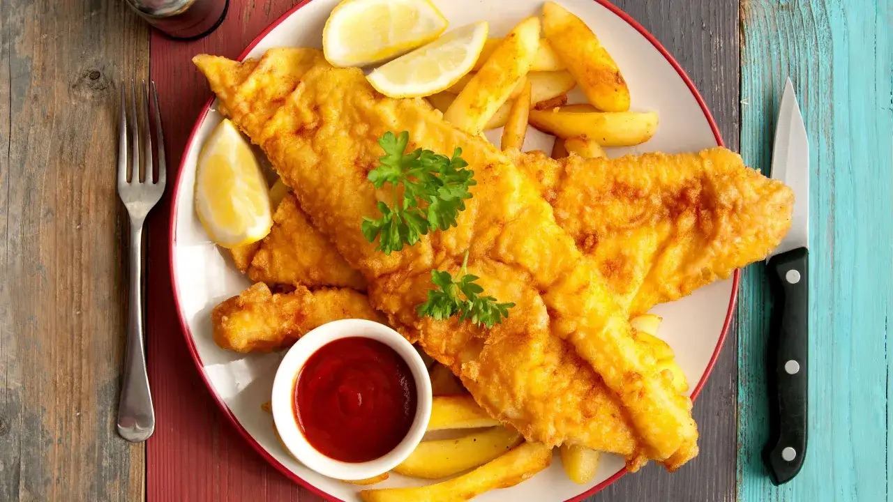 Pyszne Fish and Chips przepis: złociste ryby w cieście, chrupiące frytki, cytryna i ketchup. Idealne danie na obiad.