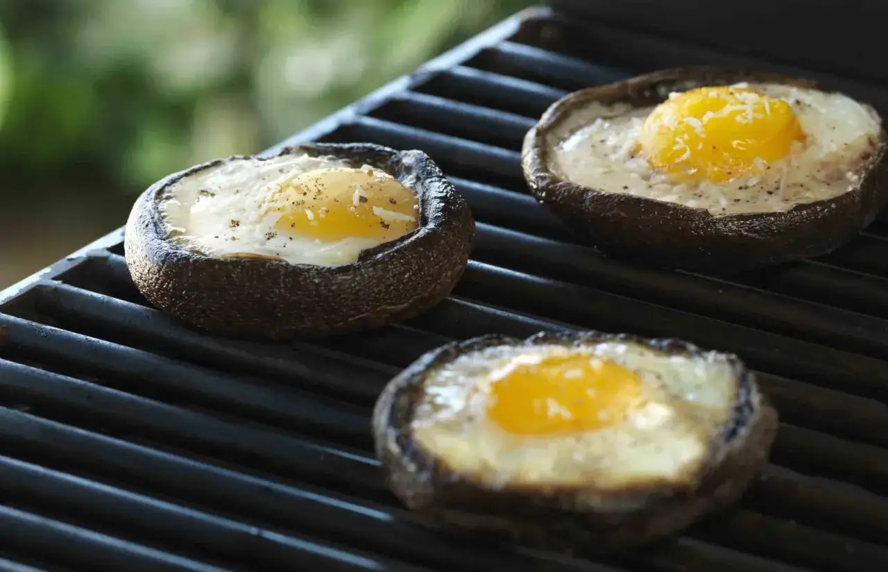 Trois œufs au plat cuits dans des champignons portobello sur un barbecue. Un délice d'oeuf barbecue.