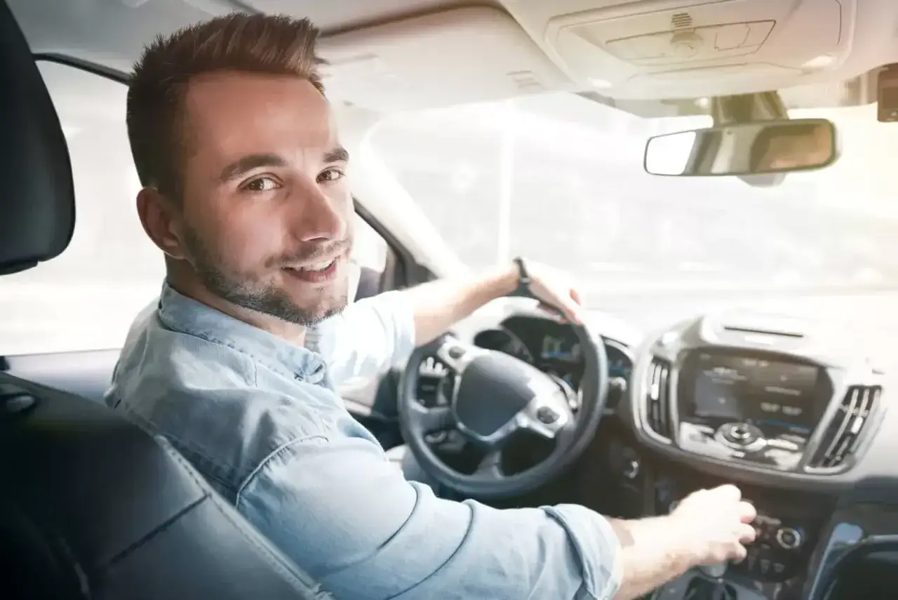 Uśmiechnięty kierowca za kierownicą, gotowy do kolejnego zlecenia uber praca.