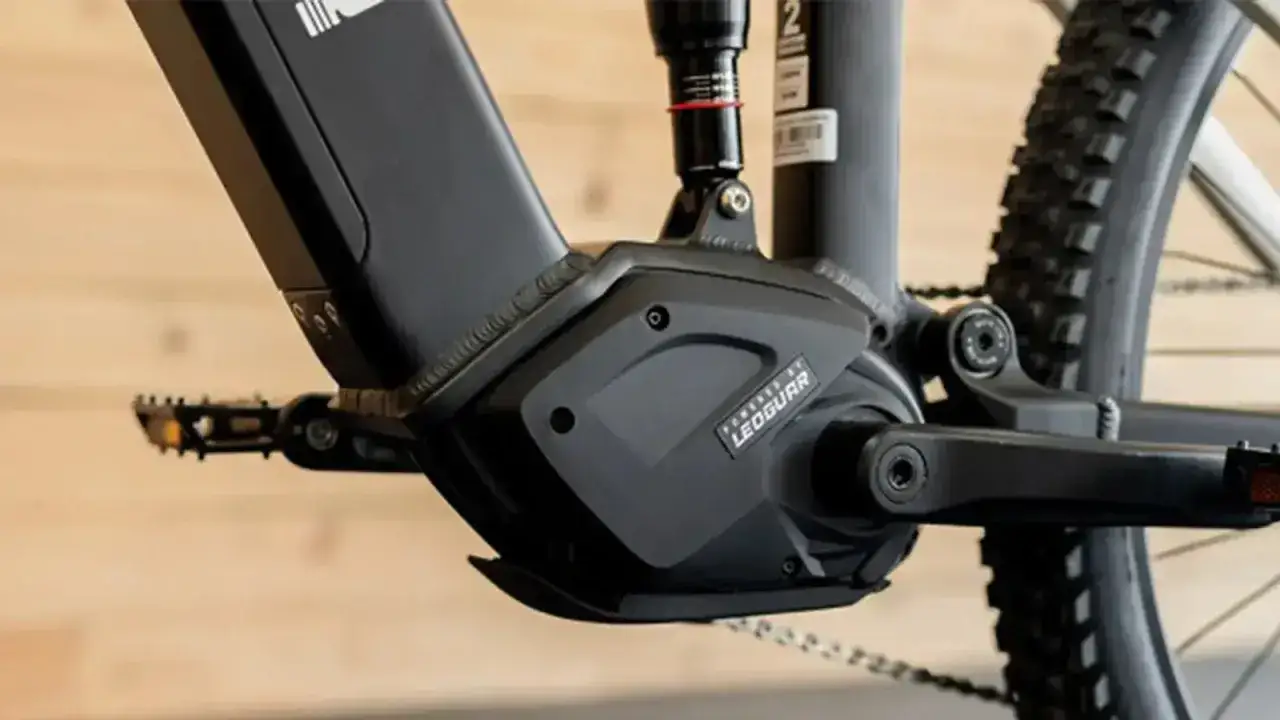 Gros plan sur le boîtier moteur d'un vélo électrique, potentiellement un modèle 500w ou 1000w, avec pédales et roue arrière visibles.