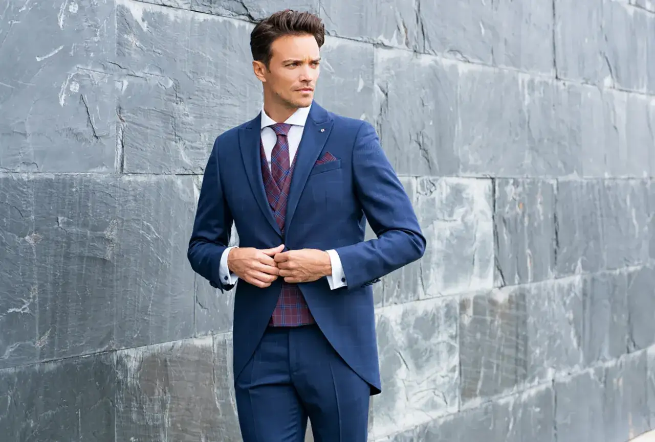 Elegante outfit boda hombre: traje azul a cuadros, chaleco a juego, corbata burdeos y pa&ntilde;uelo.