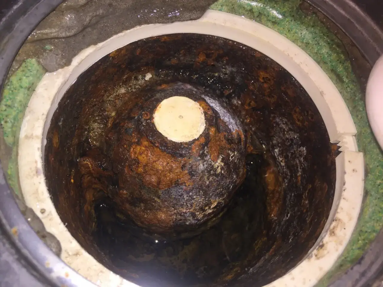 En igensatt och rostig golvbrunn som beh&ouml;ver rensas. Vatten och smuts har samlats i botten.