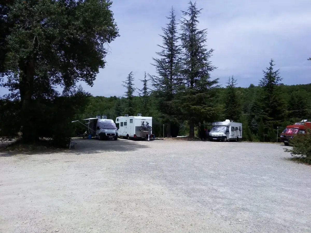 Aire de camping-car dans les Gorges du Verdon. Plusieurs camping-cars stationn&eacute;s sous les arbres, pr&ecirc;ts pour l'aventure.