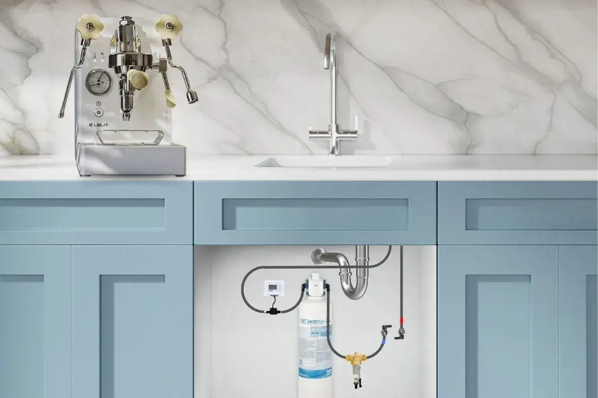 Installation d'un filtre &agrave; eau maison sous l'&eacute;vier, avec une machine &agrave; expresso sur le comptoir.
