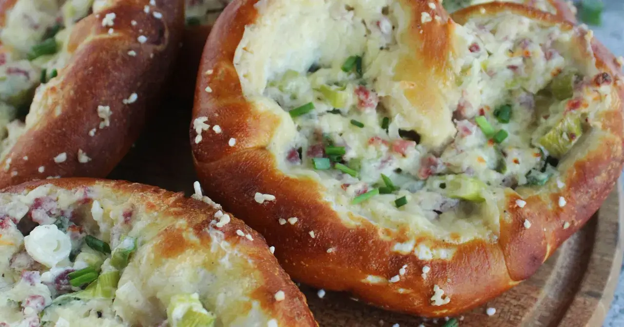 Herzhafte Brezel mit Flammkuchen-Füllung: Speck, Lauch und Käse auf knusprigem Teig, bestreut mit Schnittlauch.