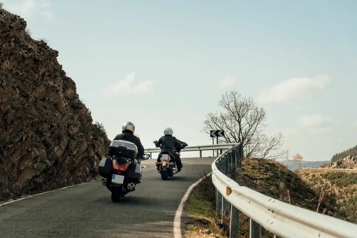 Motocykliści przemierzają krętą drogę w górach, ciesząc się wolnością i odkrywając nowe **rodzaje turystyki**.